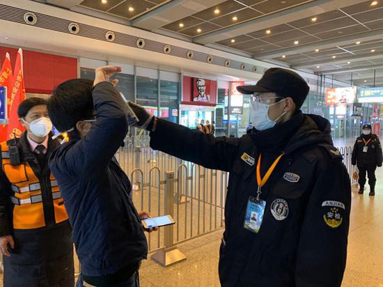 2月8日上午,虹桥火车站工作人员对乘客进行测温