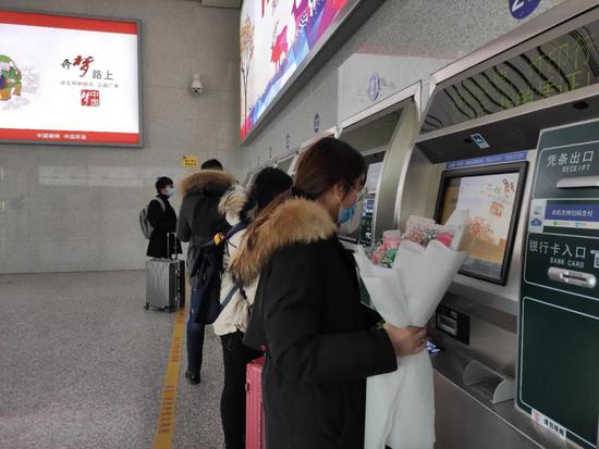 ▲旅客在黄山北站自动售取票机前取票（陆杨 摄）
