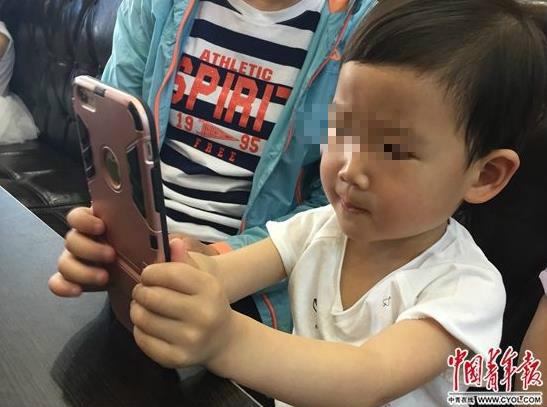 图说:5月14日,天津一家餐厅,一名3岁儿童在等餐期间,用家长的手机聚精会神玩儿游戏。 据中青网