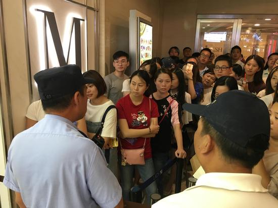 图片说明:民警正在告知排队的人暂停营业的消息。