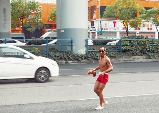 肌肉大爷在公路上倒跑健身。 微博网友@叶东东_诸星丹 图