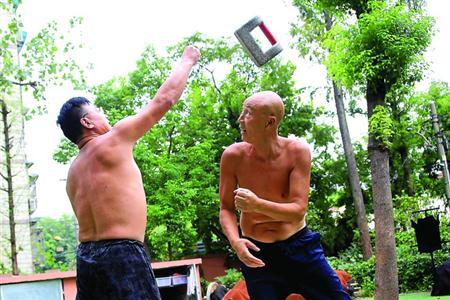 周为民(左)和姜志顺练习双人花锁,两人相距一米左右站定,然后一人将石锁抛出,一人稳稳地用肩、肘或者干脆背过身去接住,配合默契,简直像一个人在抛接一样。