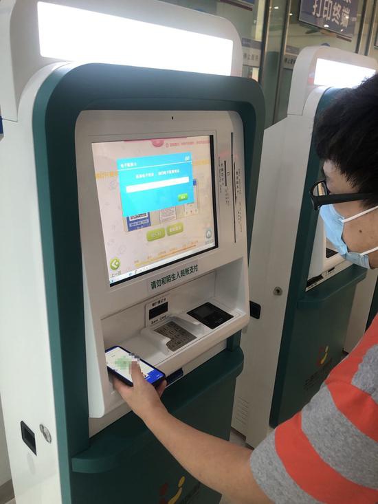 沈先生走到自助机旁,打开“随申办”APP,出示孩子的“亲属二维码”,扫码进行个人支付与医保结算。本文图片均为 上海市儿童医院 供图