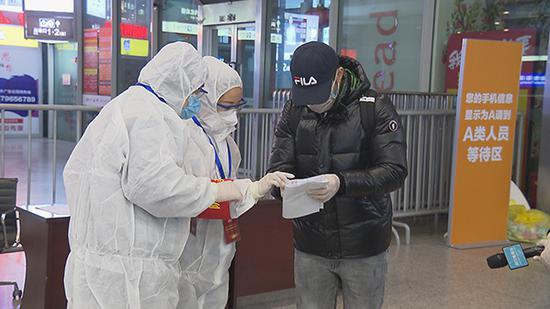 2名身穿防护服的双语志愿者，在虹桥高铁站为来沪外籍旅客提供服务。