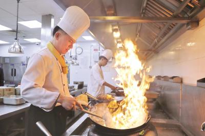 黄国平在对年夜饭菜品试菜烹饪。本报记者袁婧摄