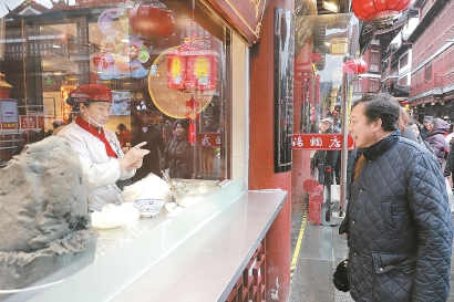 上海豫园宁波汤团店入口处,师傅隔窗展示手工汤圆制作。这几天,该店凌晨2时开工,35位师傅每天做10万多只汤圆。本报记者 海沙尔 摄