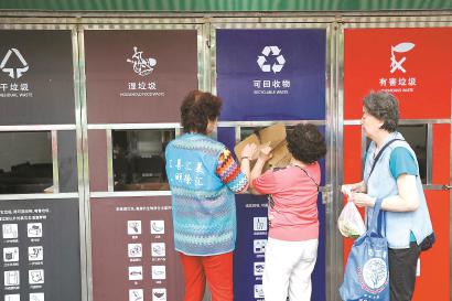 居民在垃圾箱房前分类投放垃圾。