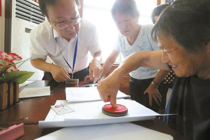 村民在工作人员指导下进行交房签约。本报记者 张海峰 摄