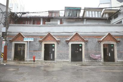 红砖老建筑灰色尖顶门头上雕着“梅兰竹菊”。