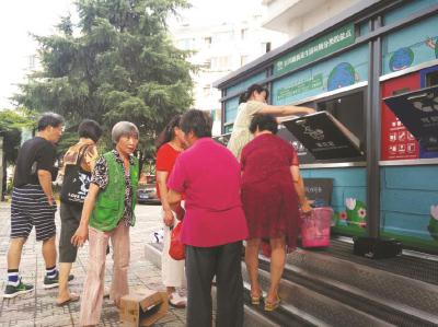 在富仕名邸(一期)小区新改造的垃圾厢房前,居民定时定点分类投放垃圾,社区志愿者进行现场指导。