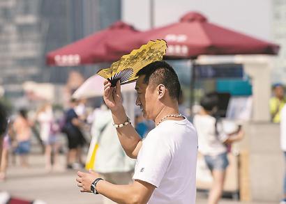 一名游客用折扇抵挡灼热的阳光。 本报记者 张驰 摄