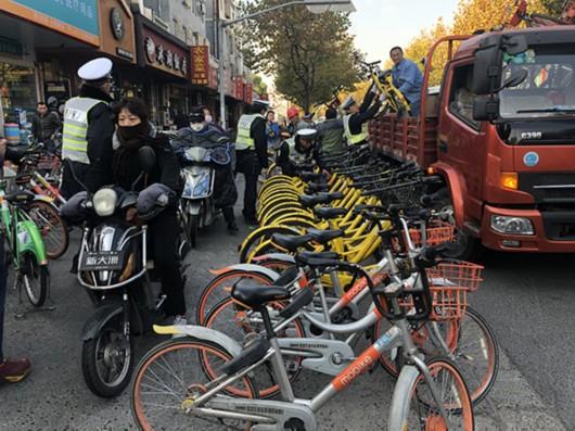 图片说明:工作人员正在清理违停共享单车。
