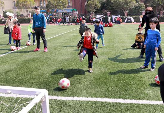 3月10日,在上海市浦明师范学校附属小学举行的校园开放日活动上,一名幼升小儿童在该校师生的辅导下练习踢球射门。张锁庆 摄