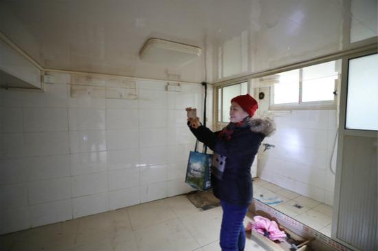 图说:居民丁阿姨在已搬空的房内拍照留念。 本报记者 周馨 摄