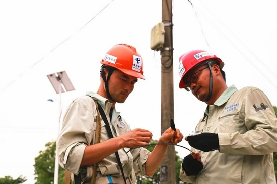 (7月7日,上海崇明新河镇金桥村,35度高温,接到用户报修后,电信维护人员赶赴现场检修线路。)