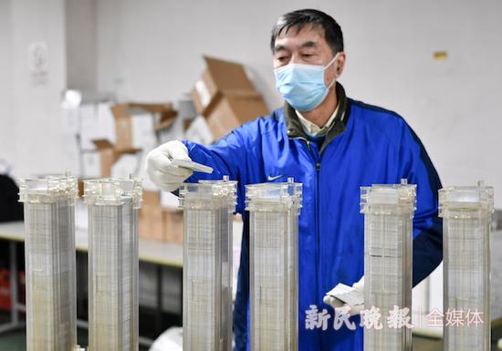 图说:工作人员将卡片放入清洗机 新民晚报记者 陈梦泽 摄(下同)