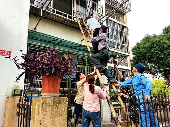 图说:保安队长王耀平爬上扶梯,紧紧托住老人身体