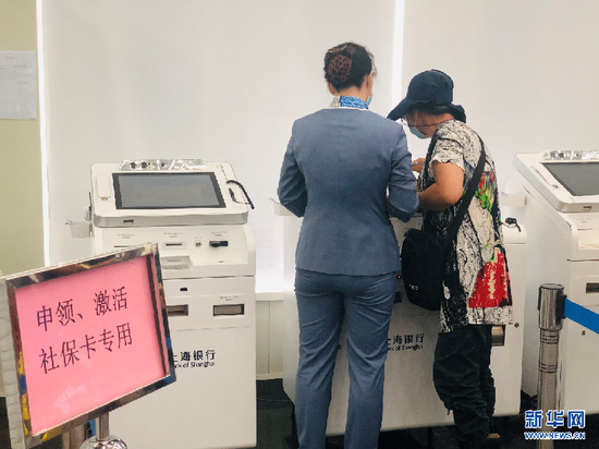 图为市民在上海银行临汾路支行工作人员帮助下换领新社保卡。新华网 李硕摄