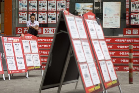 上海某房产中介门口，销售员坐在台阶上看手机。