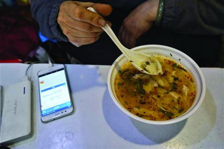 在吃饭时何文妹也不忘盯着手机 本版照片/晨报记者 岳强