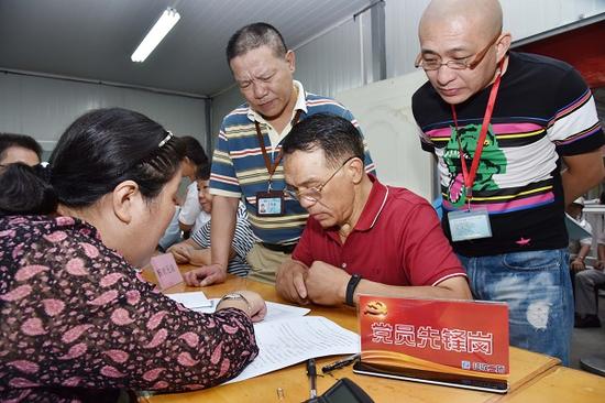 图说:工作人员在签约现场回答居民疑问。陈泰明 摄