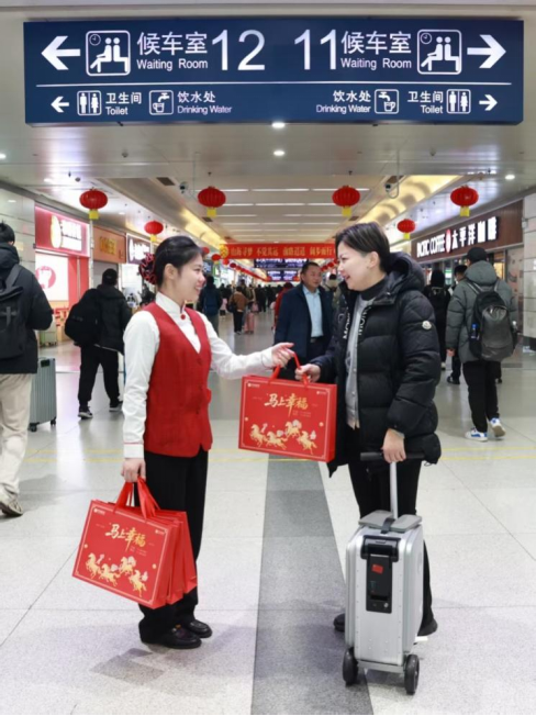 图：2月10日，中信银行上海分行工作人员在上海火车站内为春运旅客送上新春福袋（余世佳 摄）
