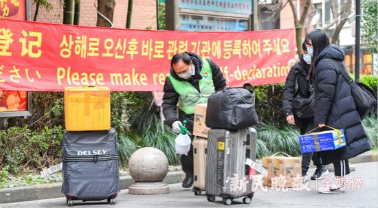 图说:保安给回沪外籍人士的行李进行消毒。新民晚报记者 孙中钦 摄