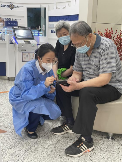 工作人员指导老年客户通过手机银行预约现金
