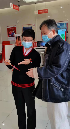 中信银行上海淮海路支行工作人员向客户介绍手机银行功能，让客户疫情期间足不出户办理业务