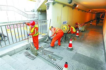 静安大统路地道,市政养护人员正在清理下水口的垃圾,确保台风期间排水通畅。本报记者 蒋迪雯 摄