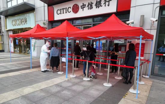 中信银行上海金山支行工作人员在网点门口询问客户业务办理需求，做好分流引导