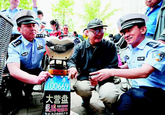 5月7日,在太原市交警支队迎泽一大队电动自行车登记服务站,民警为第一辆电动自行车安装上号牌。 记者寇宁摄