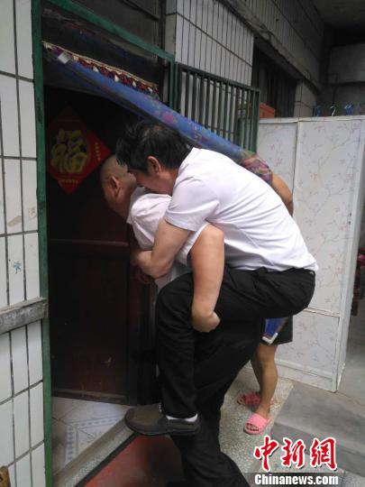 8月11日,张喜平结束了半月多的抢救和治疗,康复出院。图为张喜平的弟弟背其进家。 范丽芳 摄