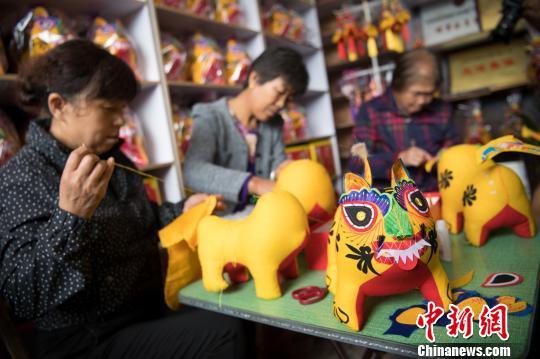 农家小院,一畦菜地,五位妇女屋中闲聊,手中都在不足半米长的金黄小虎上编缝剪绣。这是山西长治市黎城县北桂花村不少农家院内的场景。 武俊杰 摄