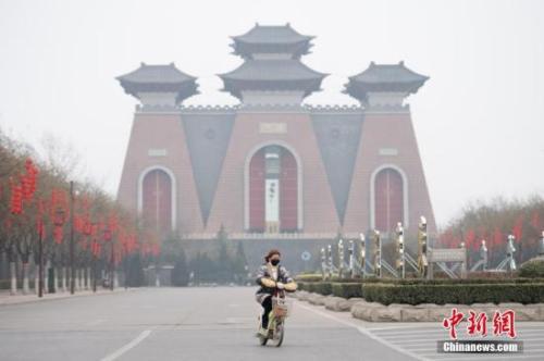 资料图:山西省临汾市,市民戴口罩经过当地地标建筑“华门”。中新社记者 韦亮 摄