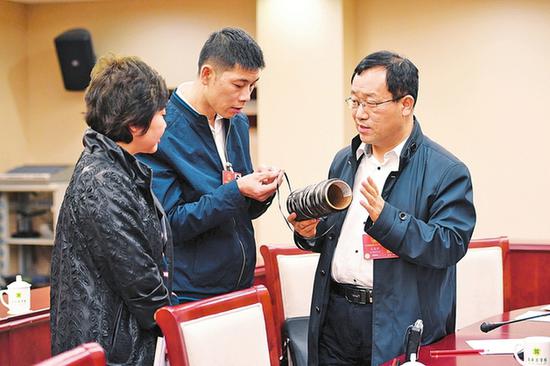吕春祥(右一)向其他代表介绍碳纤维的作用。