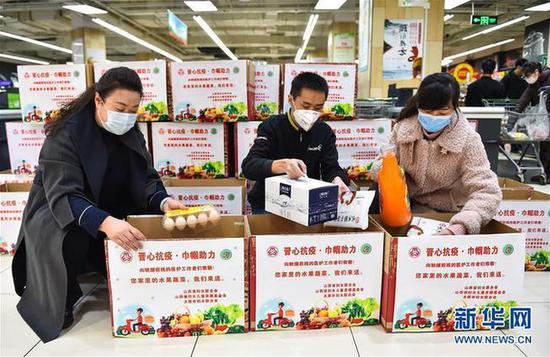 2月10日,在太原市永辉超市,工作人员将生活物资放入“暖心包”。新华社发(柴婷 摄)