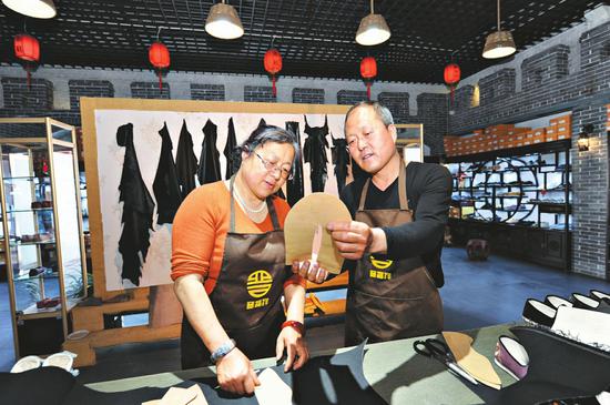 王国中(右)在店内制鞋。