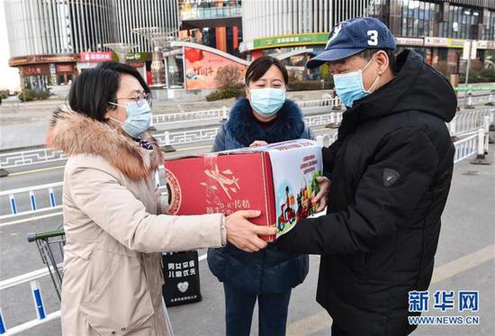 2月10日,工作人员将“暖心包”送给支援武汉医疗队队员王芳的父亲(右)。 新华社发(柴婷 摄)