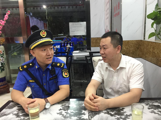 唐槐执法中队市容队长李园田与某烧烤店老板交谈