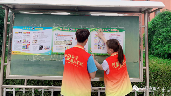 社工在校园内号召全体师生珍爱生命远离毒品、并且介绍毒品仿真模型、张贴海报