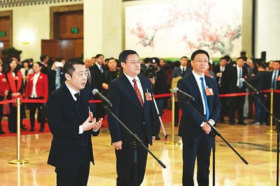 全国人大代表贾樟柯(左一)在“代表通道”接受采访。本报记者 李联军摄