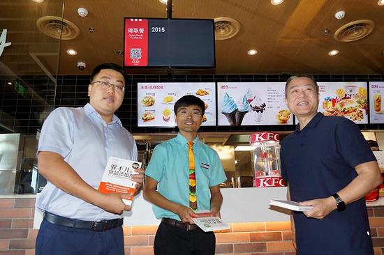 中国经济网常务副总经理雷越向肯德基餐厅管理人员赠送食品安全科普书籍