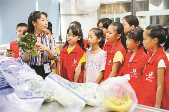 市农检中心副主任王多加给参加活动的孩子讲解食用农产品检测流程。