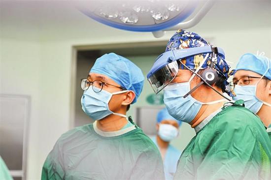 ▲鲍世韵（左二）带着AR眼镜在董家鸿院士的实时指导下进行手术。