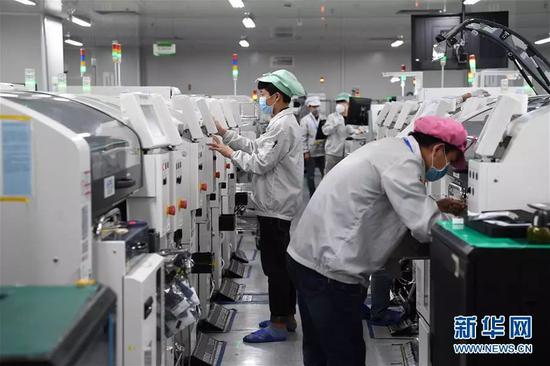 2月10日,在深圳龙岗区一家工业园区的生产车间,复工的工人佩戴口罩工作。