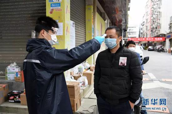 在深圳市宝安区新安街道海乐社区的城中村,工作人员为居民测量体温(2月9日摄)。