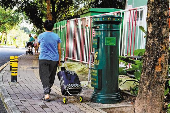 福田区梅岗路，一位市民正走过一个邮筒。