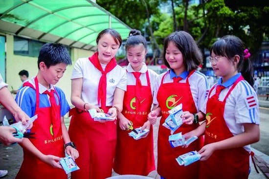 图为黄稳带领学生回收奶盒(左二为黄稳)