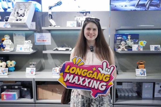 外国友人刘欢在机器人6S店手持Langgangmaxxing KT板合影。（叶惠玲 摄）